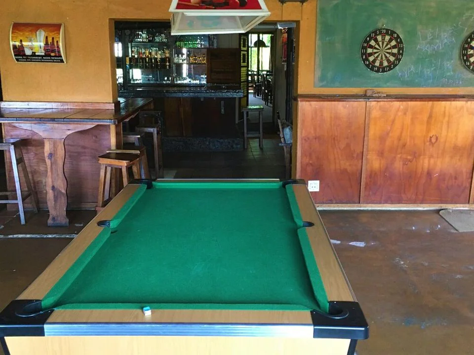 The pool table in the games room, with a dartboard on the wall and the bar behind