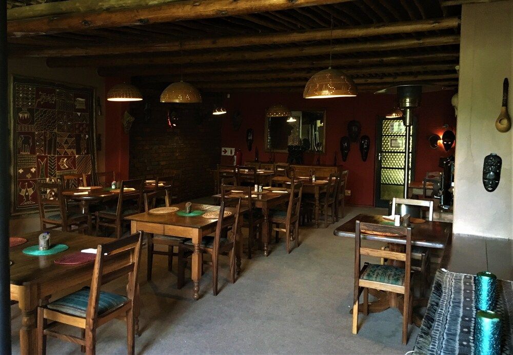 The dining room from the other end, with red walls, carved masks and woven table mats